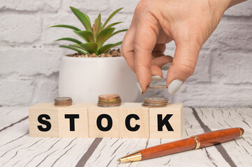 Hand putting coins on stack stair as step growing growth and wooden cube block with word STOCKS. Investment and save money concept