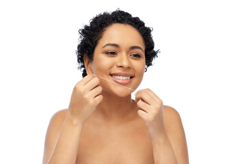 beauty, health and people concept - close up of of happy smiling young african american woman cleaning teeth with dental floss over white background