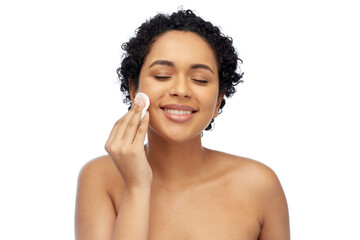 beauty, skin care and people concept - portrait of happy smiling young african american woman with bare shoulders cleaning her face with cotton pad over white background