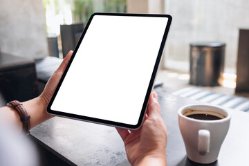 Mockup image of a woman holding digital tablet with blank white desktop screen in cafe