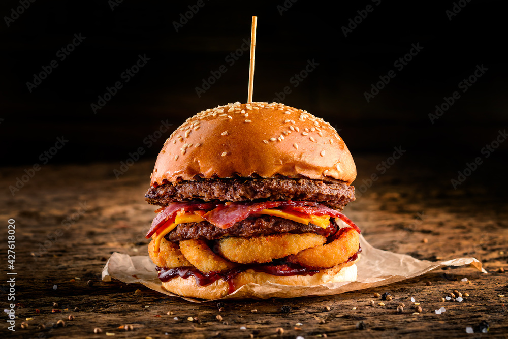 Wall mural close-up of a tasty double hamburger with cheese and deep fried ground meat on a wooden table