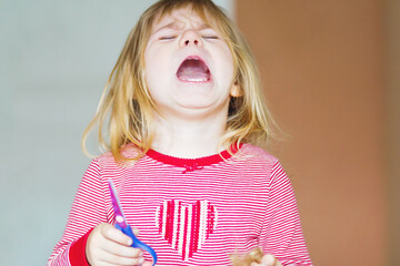 Little cute toddler girl making experiment with scissors and cutting hairs. Funny baby child cuts her pony herself at home. Trouble