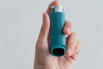 Human hand picking up an asthma inhaler