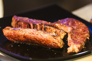 Juicy steak on a plate. A few pieces of lightly roasted meat on a black plate. Close-up and short focus.