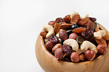 Different types of nuts in a wooden bowl isolated on white background. Nutrient dense vegan snacks. Clean eating concept. Close up, copy space for text, top view, flat lay.