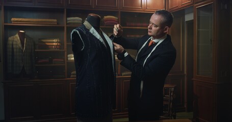 Fototapeta Cinematic shot of professional tailor taking measurements for creation of custom high quality tailored suit in luxury tailoring atelier.Concept of fashion, handmade, hand craft, couturier and business obraz