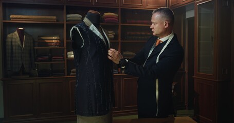 Cinematic shot of professional tailor taking measurements for creation of custom high quality tailored suit in luxury tailoring atelier.Concept of fashion, handmade, hand craft, couturier and business
