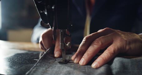 Macro shot of experienced tailor is sewing custom handmade high quality apparel in ancient luxury...