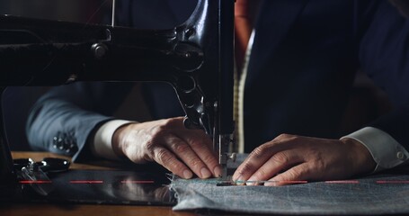 Close up shot of experienced tailor is sewing custom handmade high quality apparel in ancient luxury traditional tailoring workshop. Concept of industry, handmade, hand craft, couturier and tradition. - obrazy, fototapety, plakaty