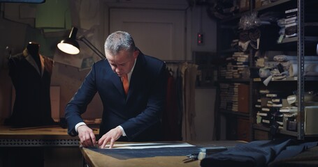 Cinematic shot of experienced tailor is measuring fine quality fabric for creation custom haute...