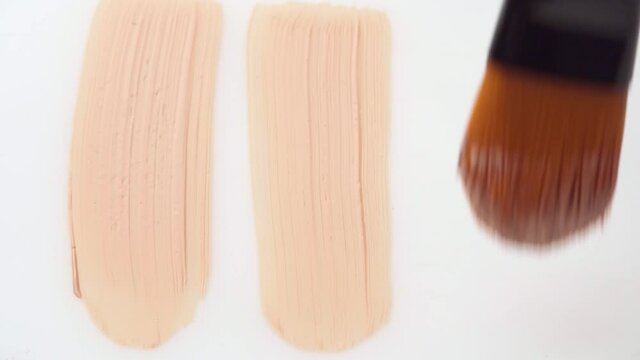 Facial foundation smudge made with a brush on white make-up palette close up