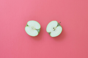 Natural green apple cut in half and fresh on pink background