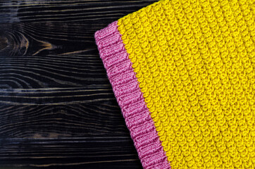 fabric knitted from yellow and pink threads on a dark wooden background top view of kopi space
