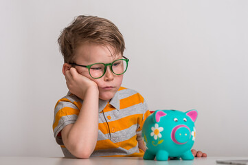 No cash money. Little caucasian kid banking money on piggy bank as wealth savings with angry face,...