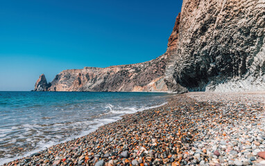 view of the sunset sea and the beach, the volcanic rock is lit by the warm sunset, sand and pebbles, volcanic basalt as in Iceland. Copy space. The concept of calmness, silence and unity with nature.