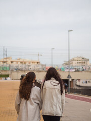 Mujeres j&oacute;venes amigas paseando por la calle con mascarilla para protegerse del coronavirus 