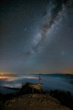 Milky way with sign board. Sign mentions "The Conqueror of the Sea of Mist at Gunung Silipat, Ai Yerweng, Betong, Yala. 607 meters above sea level. By Aiyerweng Sub District Admin Organization Office.