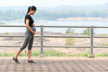 Portrait of young Asian pregnant woman walking and workout in the park.