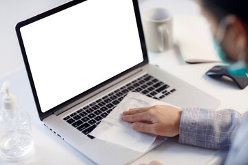 Woman disinfecting and sanitizing laptop with empty blank screen against corona virus. Antiseptic, hygiene and health concept. Copy space for text