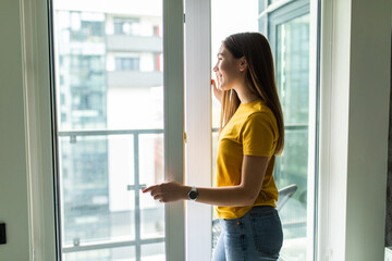 Young smile woman opening window in living room