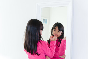 Asian Child make up beautiful little girl in the mirror preening. little beauty