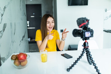 Woman sitting beside desk with laptop while filming her broadcast