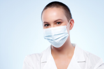 Short-haired woman doctor in medical gown wearing face mask