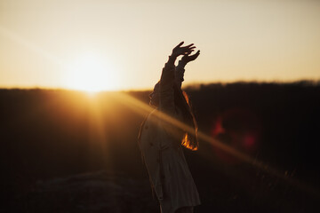 Free woman raising arms to golden sunset and sky. Freedom, success and hope concept.
