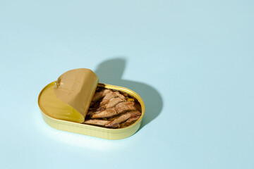Sprat with oil in an open tin can on blue background with copy space