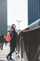 Travelers holding a cup of coffee stand watch Osaka Umeda district on the overpass with happiness...