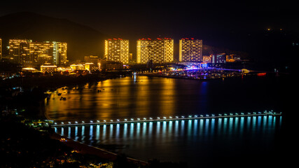 Fototapeta na wymiar Sanya scenic nightscape with long pontoon in Sanya Bay and Banshan peninsula view in Sanya Hainan China