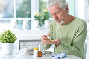 Portrait of sad sick senior man with pills