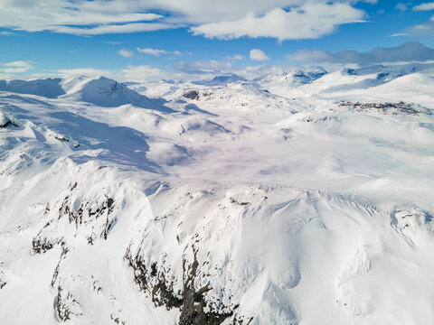 Spectacular panoramic view over snowcapped mountain peaks, ridges and frozen highland tundra in Jotunheimen, Norway.