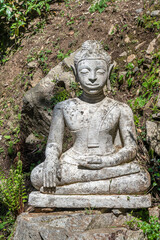 Antique stone outdoor buddha sculpture in Scherrer Park in Morcote, Switzerland.