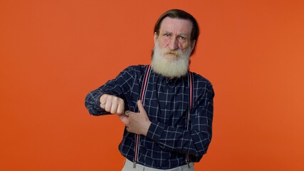 Obraz premium Upset elderly bearded gray-haired man showing thumbs down sign gesture, expressing discontent, disapproval, dissatisfied, dislike. Senior old grandfather on orange background. People lifestyle emotion