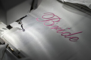 Machine embroider the inscription bride on a white satin robe.
Inscription bride with pink thread....
