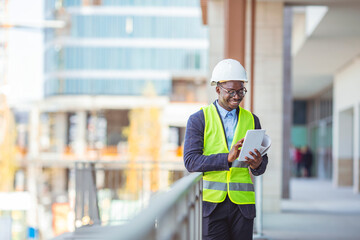 Fototapeta na wymiar Portrait of smiling Engineer / Architect looking at camera. Working on a new office building. Happy mid adult engineer. Man engineer walking on construction site, holding tablet.