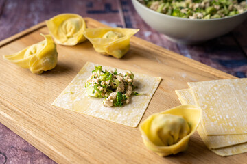 Folding instructions for vegan wonton dumplings with tofu and broccoli on wooden cutting board