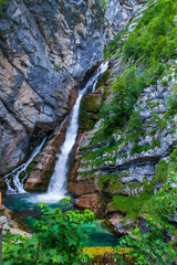 Obraz premium Waterfall in Slovenian mountains falling from rock to small lake.