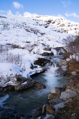 Røldal waterfall at the end of winter, mountain slopes covered with snow