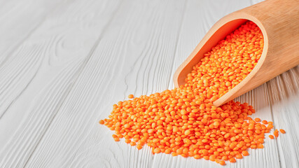 Scoop with red lentils on a wooden table with copy space