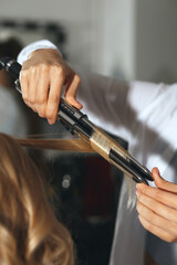 Hair stylist coiffeur making curls in beauty salon