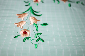 Embroidery of colourful flowers on green fabric, photographed. Close up.