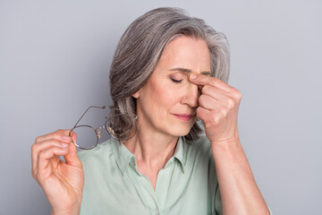 Portrait of depressed tired sick gray-haired woman feeling bad isolated over grey pastel color...