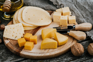 Cheese dish with organic cheeses, fruits, nuts on a wooden background. Delicious cheese snack
