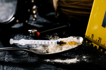 Fototapeta premium Heroin in a syringe and heroin powder on a black background. the concept of a narcotic substance