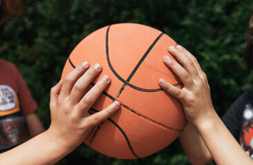 Close up of two kids hands sharing a ball. Children playing with a basketball ball. 