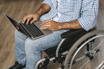 Disabled man sitting in a wheelchair and using laptop