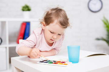 cute little girl painting something with watercolors