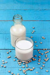 Soy milk in transparent glass with soybeans on blue wooden table. Healthy concept.